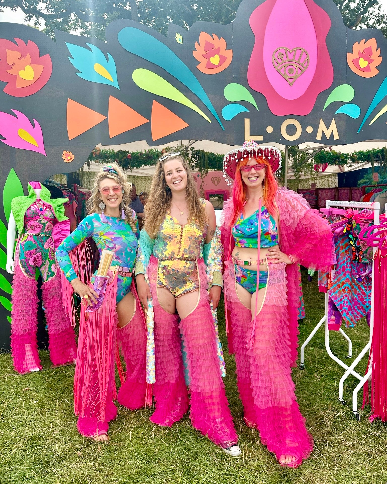 Three people wearing pink layered fringe chaps with robe