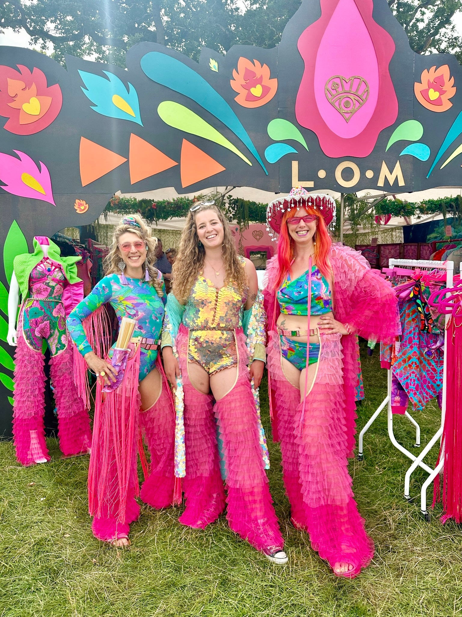 Three people wearing pink layered fringe chaps with robe